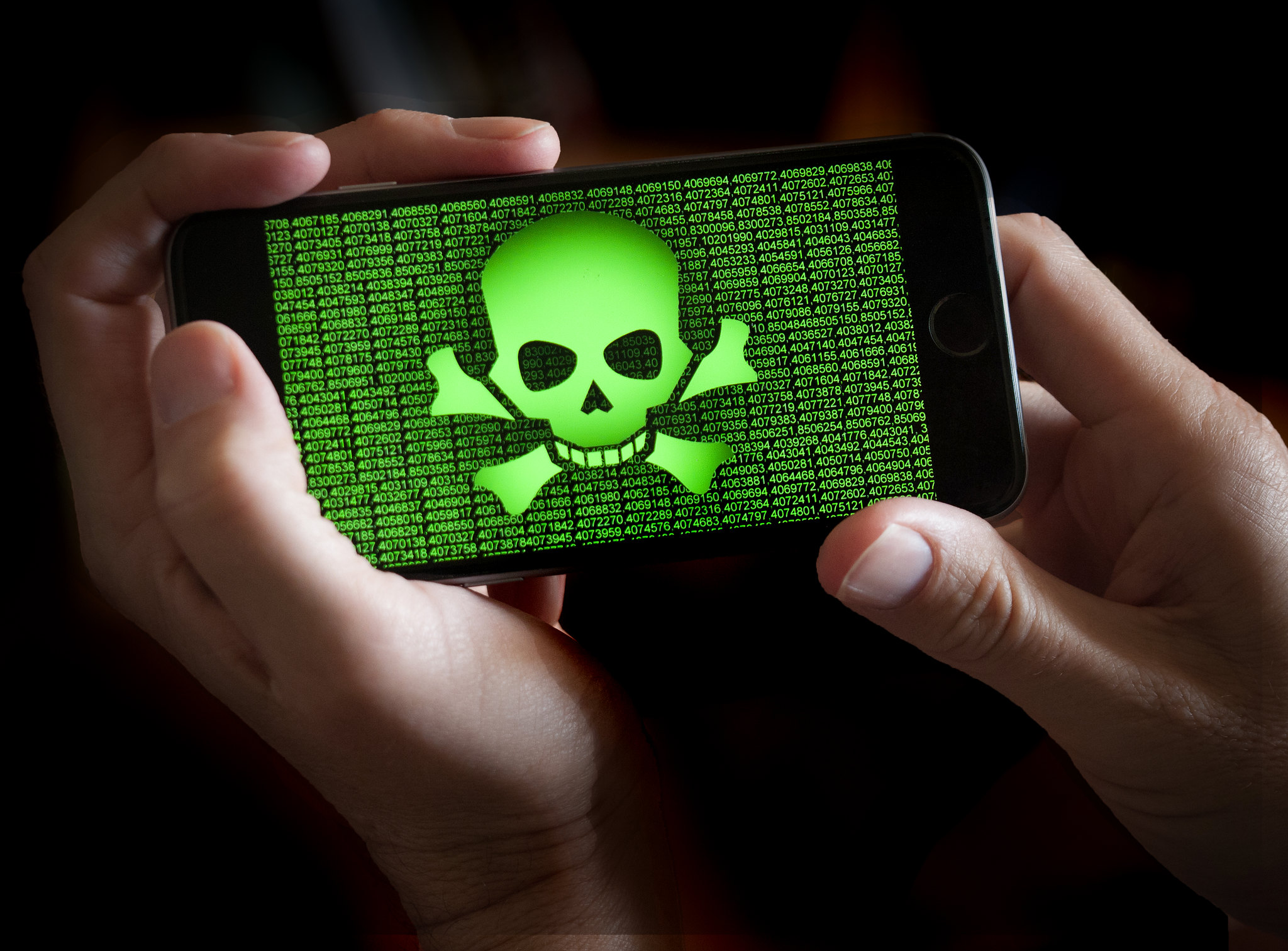 Menacing green skull and crossbones over a background of green numbers on a horizontally-held smartphone.