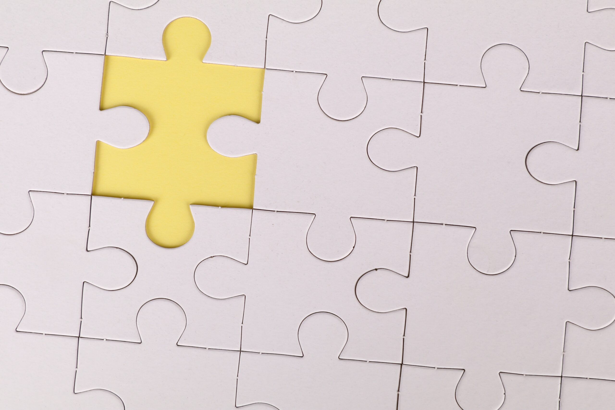 White puzzle pieces assembled with one piece missing, revealing a contrasting yellow surface