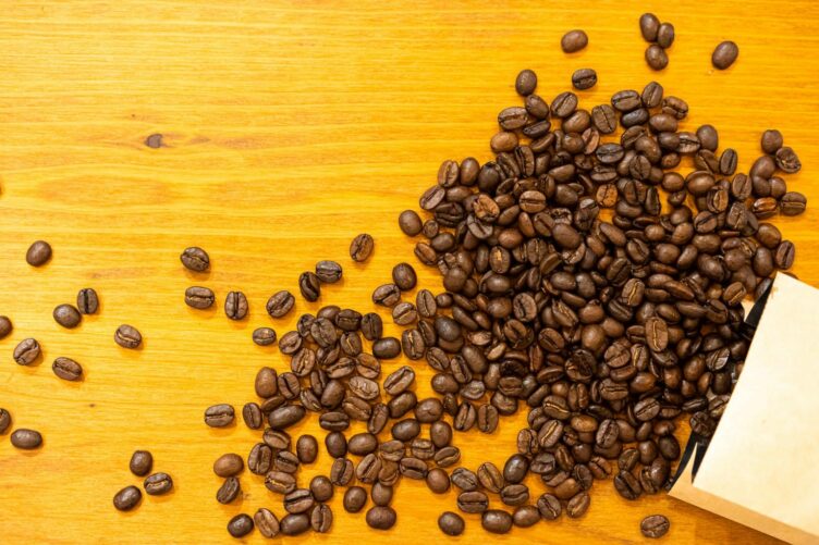 Coffee beans spilled across a wooden table