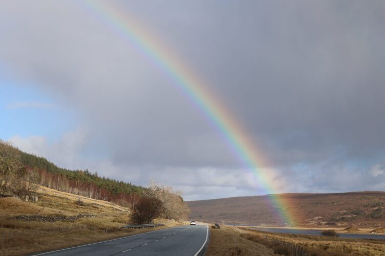 Rainbow over the road and the loch hitting the land, Scottish Highlands