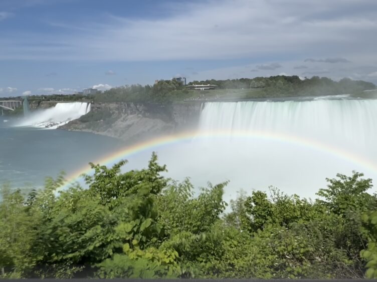 A rainbow over the Canadian Horseshoe Falls with the American Falls in the background at Niagara Falls.
